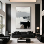 Vertical Abstract Wall Art with soft black and grey strokes displayed in a modern high-ceiling living room with a black sofa and decor