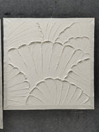 White plaster art texture painting above a chair in a styled room.