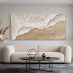 3D textured 'Shoreline' beach art above a couch with silver frame.