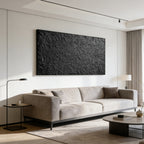 Large 3D textured abstract minimalist black wall art 'Obsidian Field' mounted on a white wall above a beige sofa in a contemporary living room.