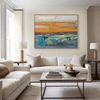 Abstract landscape art in living room. Golden and blue canvas above a white sofa.