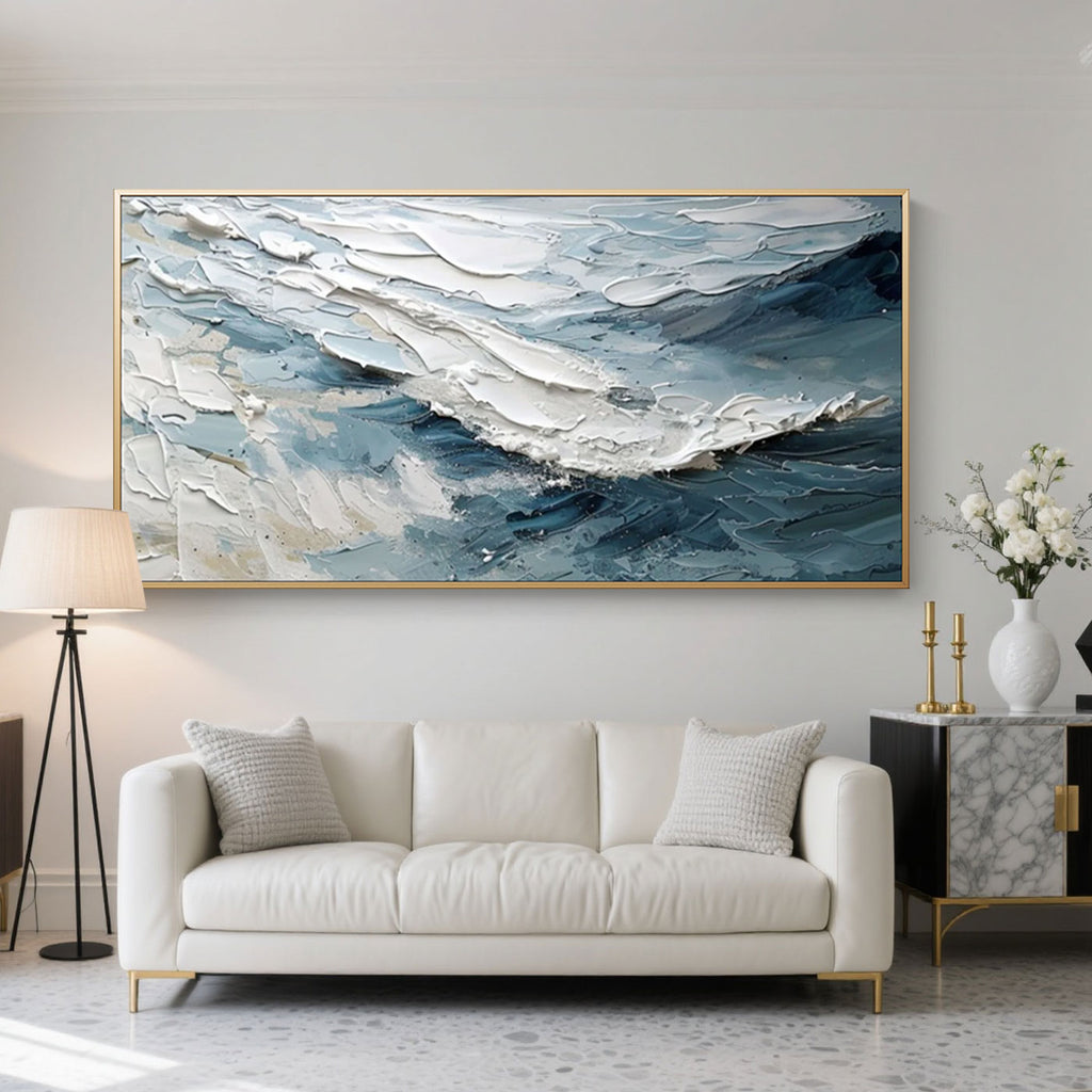 Abstract modern wave hand-painted canvas wall art 'Breakwave', textured blue-white ocean scene, framed, above white sofa.