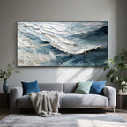 Lumi Gallery's abstract modern wave canvas painting with textured brushstrokes in blue/white, above gray sofa