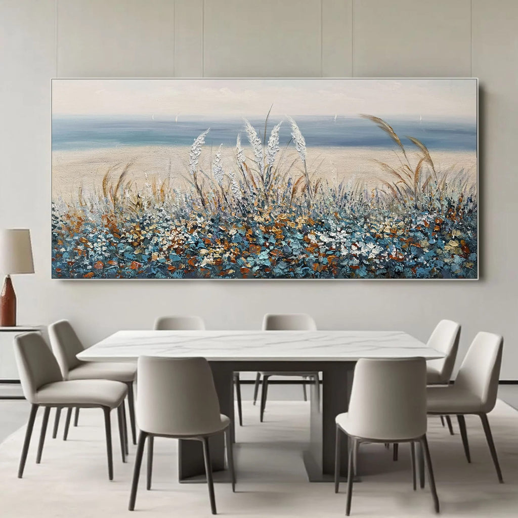Impressionist floral landscape painting with blue/orange wildflowers, sandy beach, ocean horizon, textured brushstrokes, hanging in modern dining room
