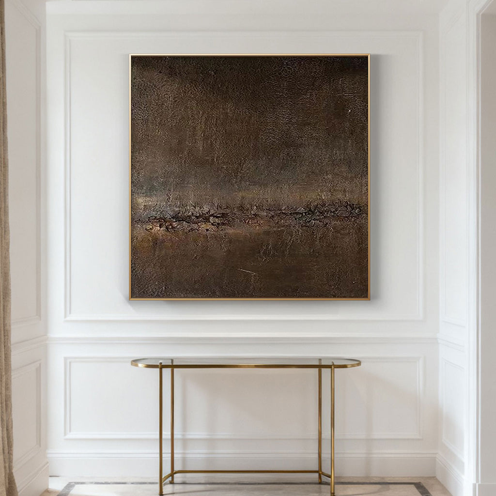 Abstract painting in a gold frame on a white wall above a gold console table.