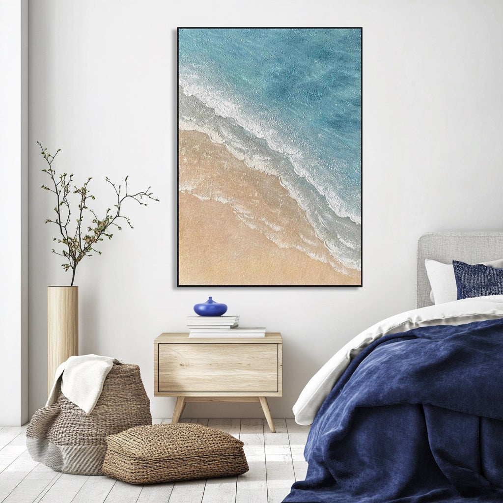 Blue and beige ocean art above a bedside table in a styled bedroom.