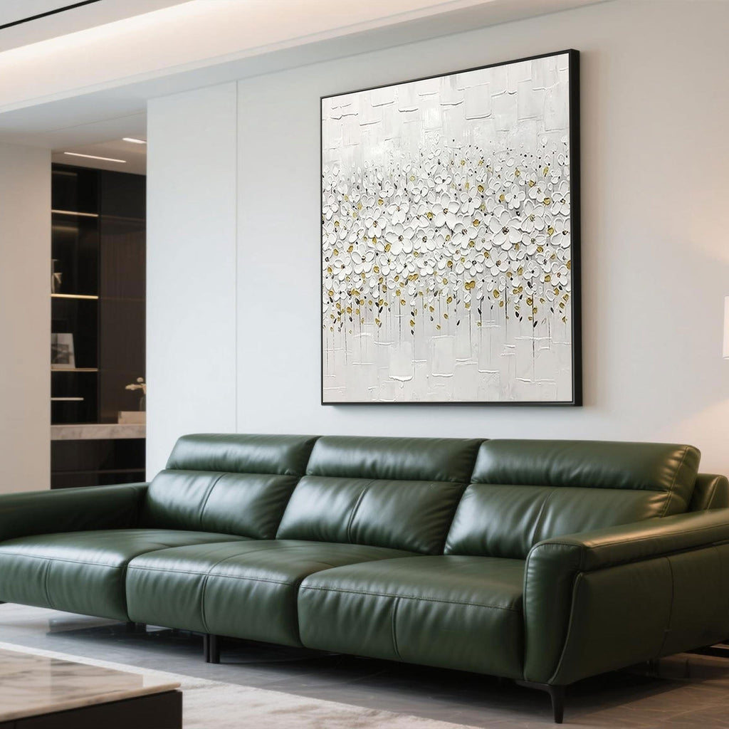 Modern white floral painting above a green leather sofa in a living room.