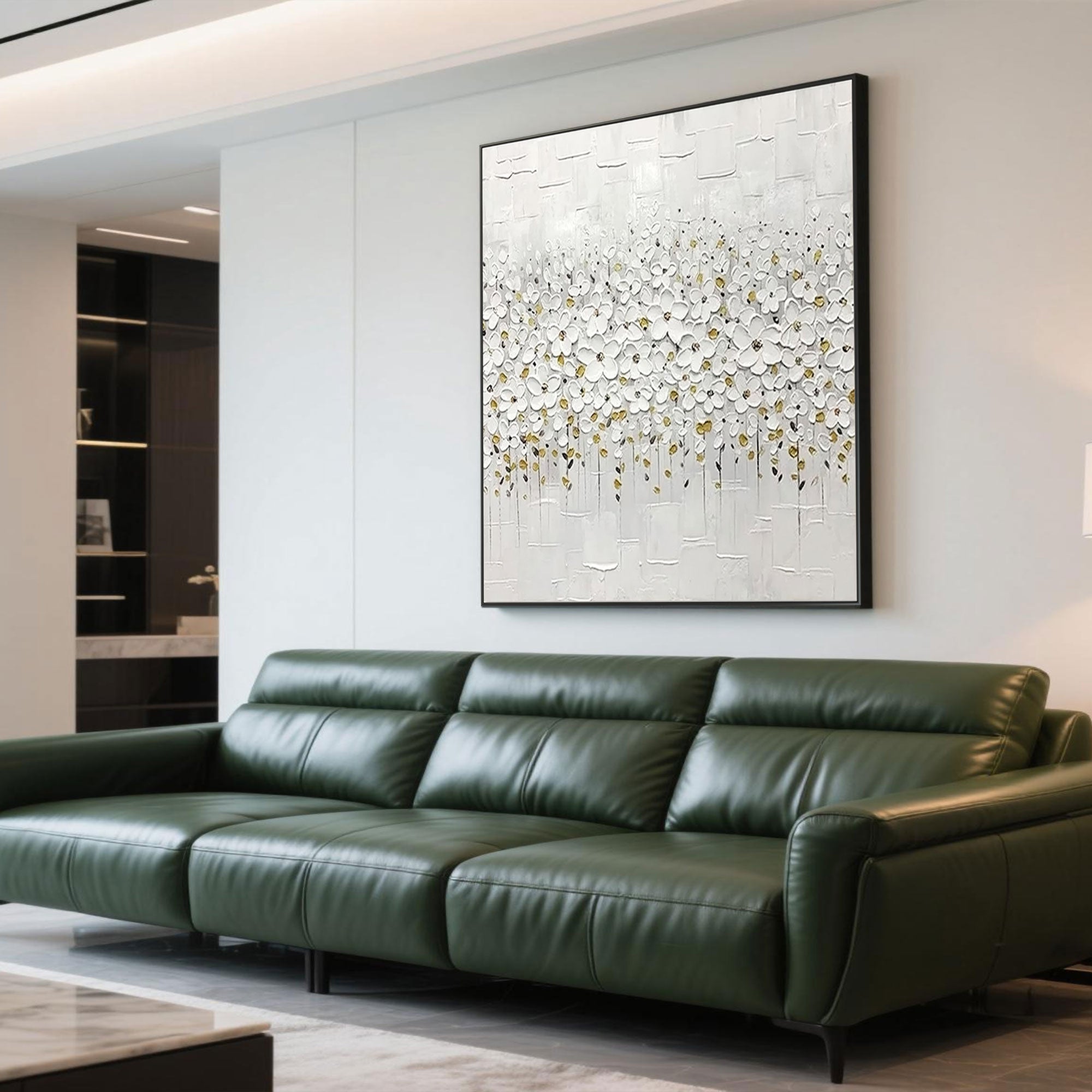 Modern white floral painting above a green leather sofa in a living room.