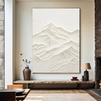 Textured mountain art above console table in living room setting.