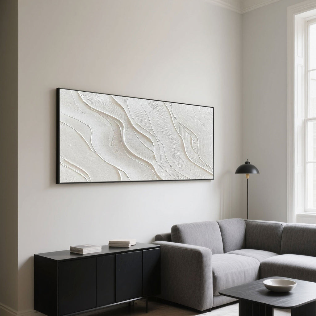 Minimalist wave art above a gray sofa and black cabinet in a modern living room.