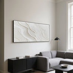 Minimalist wave art above a gray sofa and black cabinet in a modern living room.