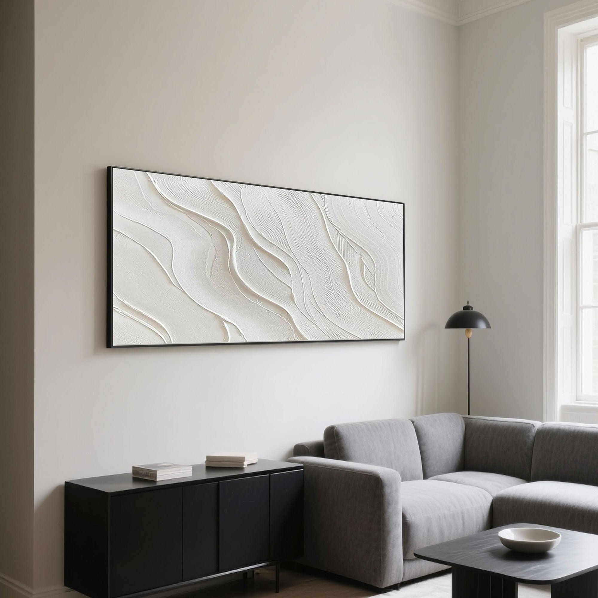 Minimalist wave art above a gray sofa and black cabinet in a modern living room.