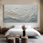 Minimalist ocean wave canvas above a bed in a modern bedroom setting.