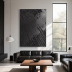 Minimalist black canvas art displayed above a leather sofa in a living room.