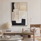 Close-up of beige and black geometric canvas art in minimalist room.