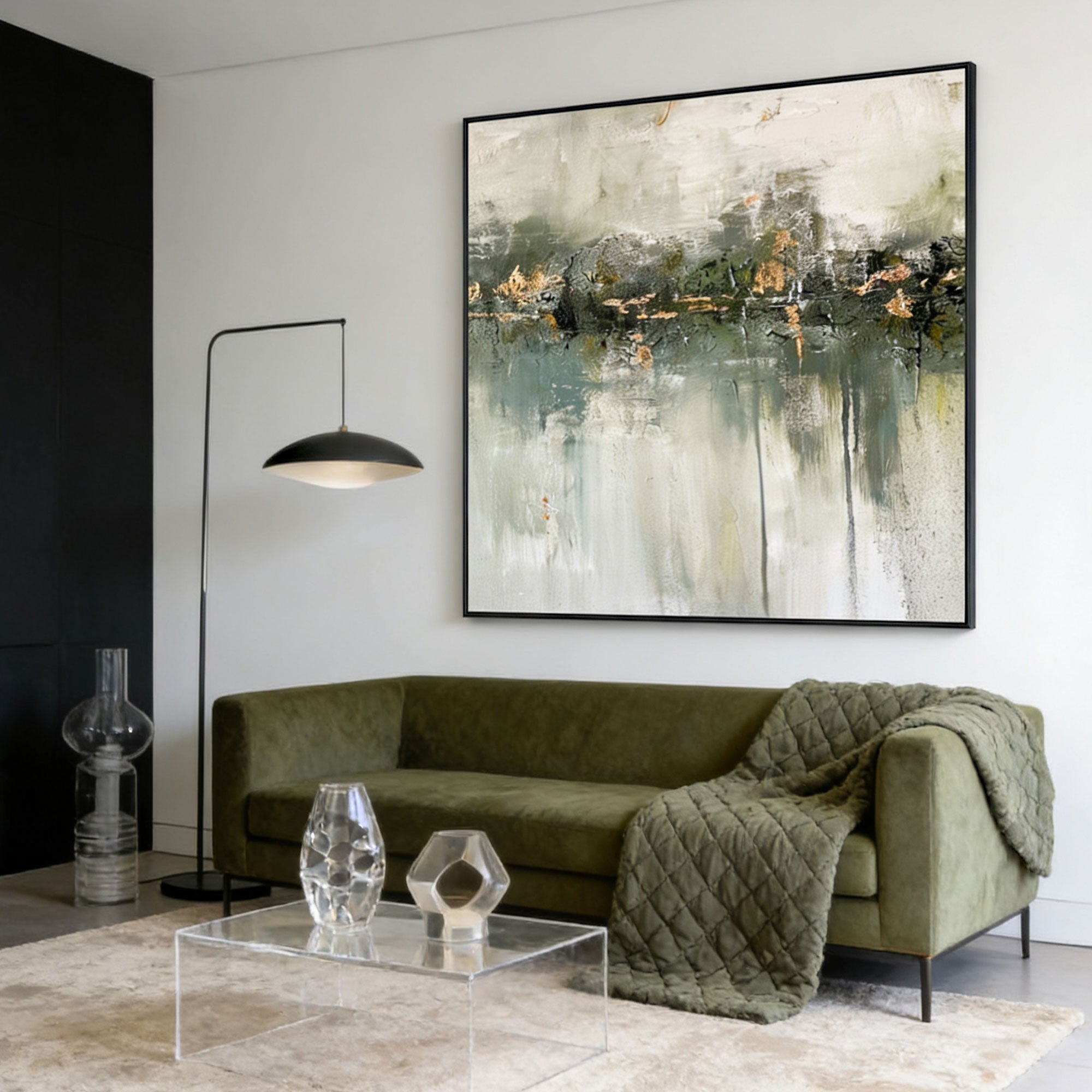 Minimalist wabi-sabi green abstract painting 'Silent Verdure' with white and gold accents, black frame, displayed in a modern living room with olive green sofa and clear acrylic coffee table.