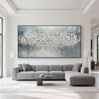Abstract blossom painting displayed above a modern grey sofa in a living room setting.