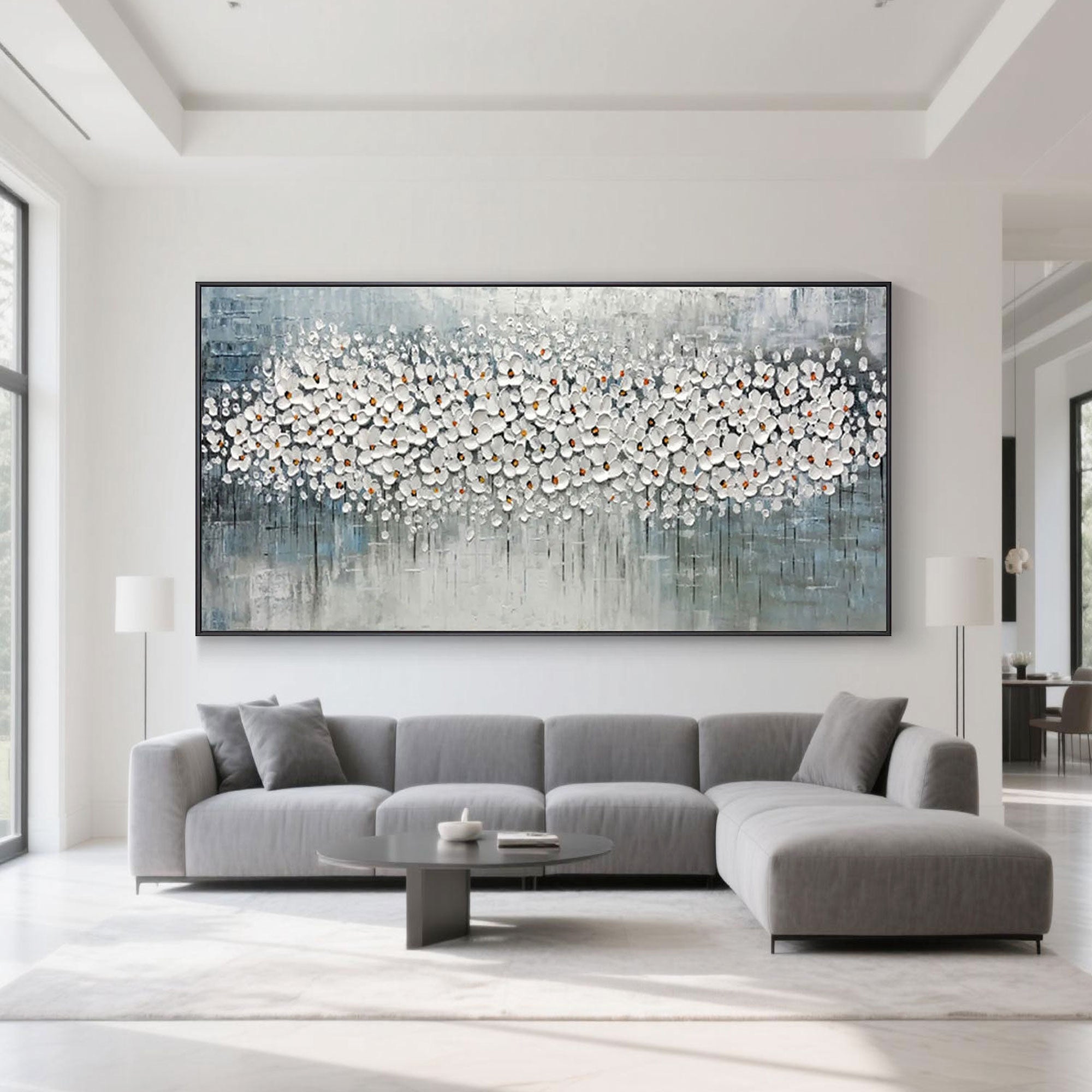 Abstract blossom painting displayed above a modern grey sofa in a living room setting.