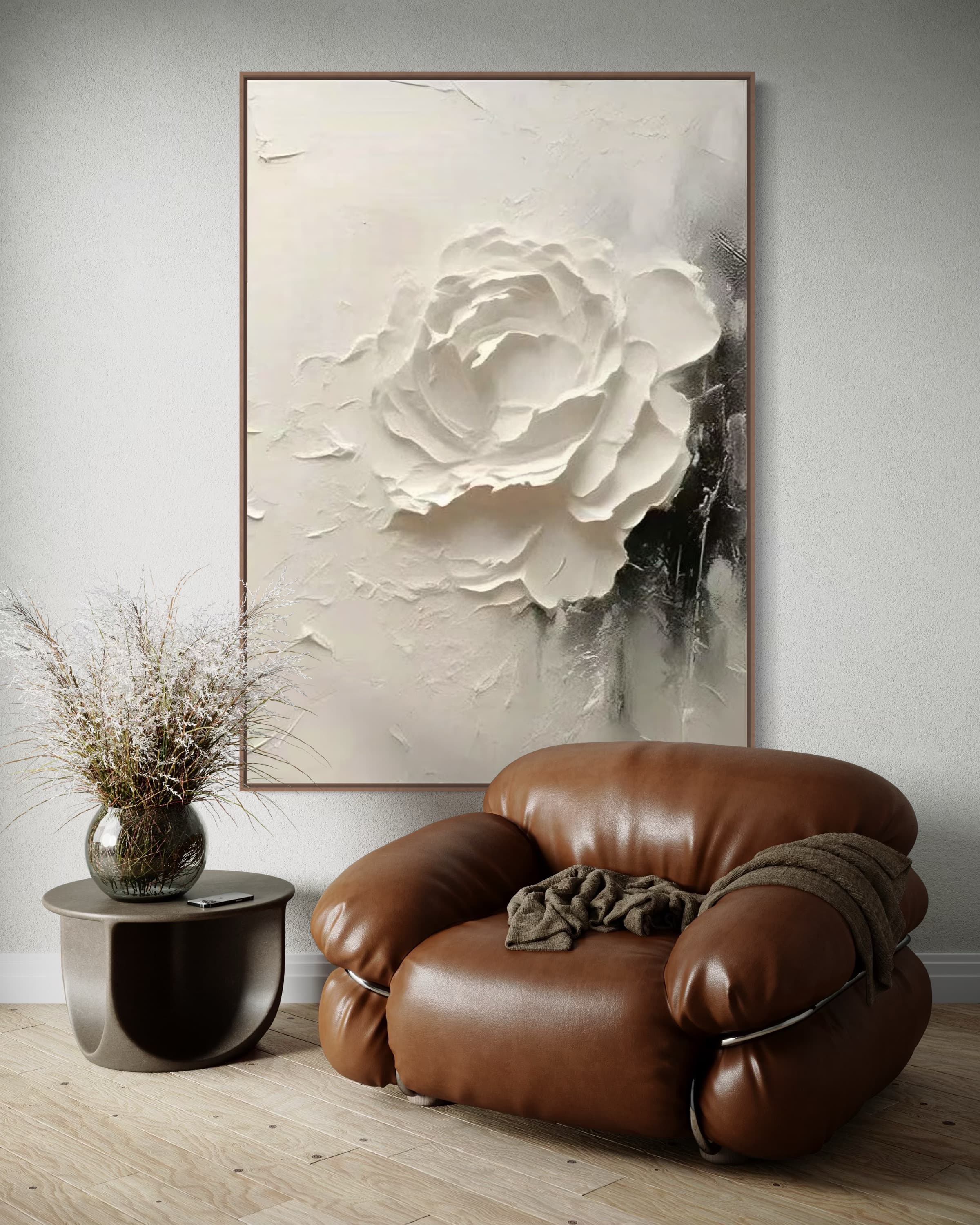 A cozy corner with a brown leather chair and a plant, the 3D - textured white rose painting above adding a sophisticated artistic element.
