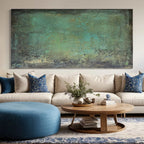 Horizontal green abstract painting above a modern low-profile sofa.