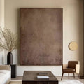 Hand-painted modern minimalist abstract wall art in muted earth tones of brown and beige with textured details, displayed in a contemporary living room.