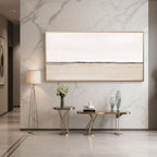 Beige canvas art in gold frame displayed above console table in entryway