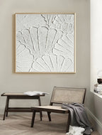 Close-up of white plaster art texture painting above a chair in a room.