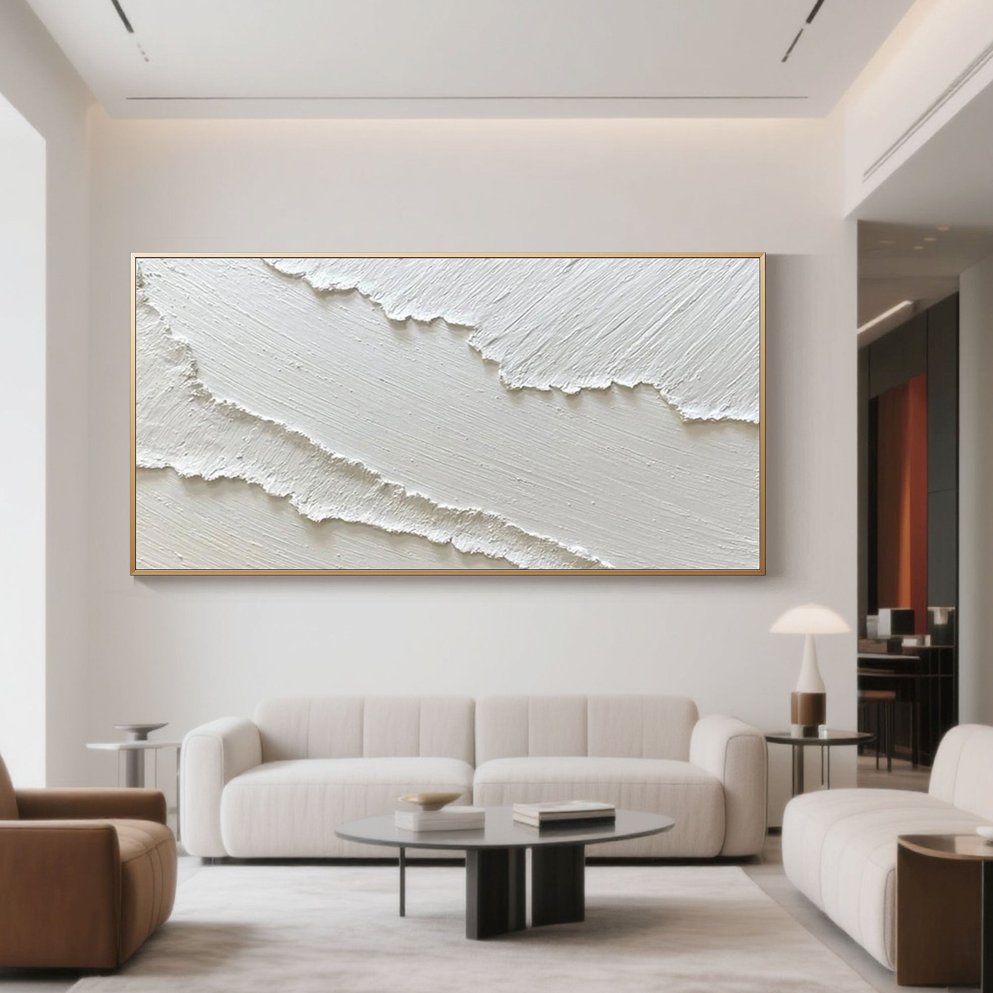 Textured white abstract ocean art with gold frame in living room setting.