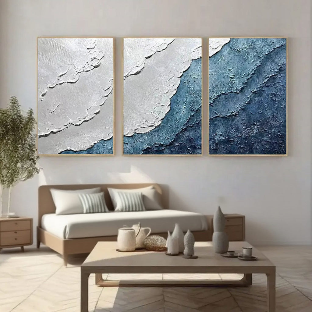 Abstract ocean canvas art above a bed in a styled room.