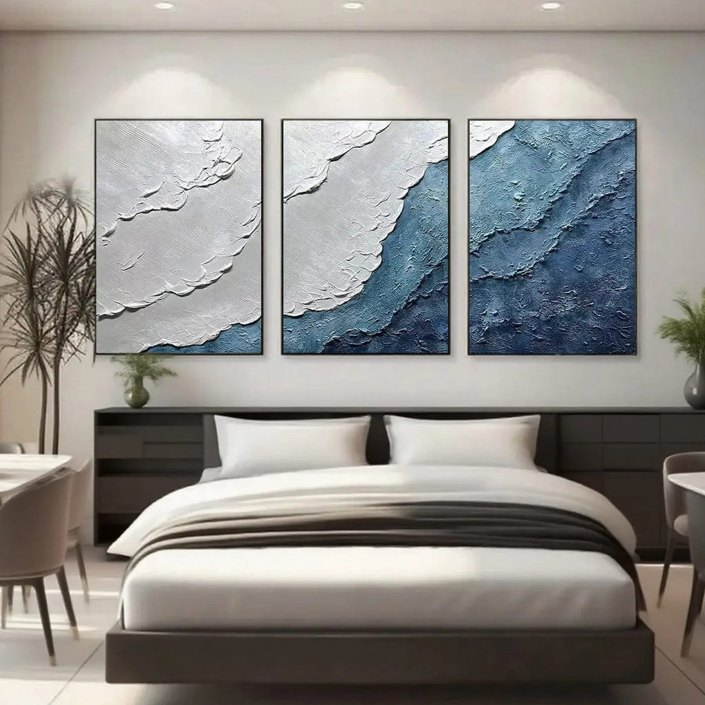 Blue and white ocean art hanging above a bed in a modern bedroom.