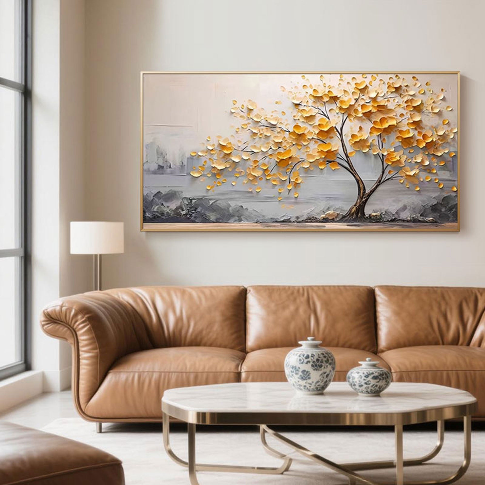 Gold abstract tree painting displayed above a brown leather sofa in a modern interior.