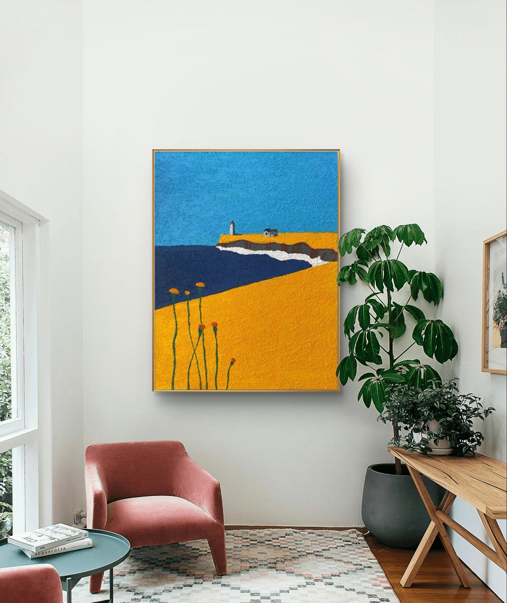 Coastal art with lighthouse, blue sky and yellow field in living room setting.