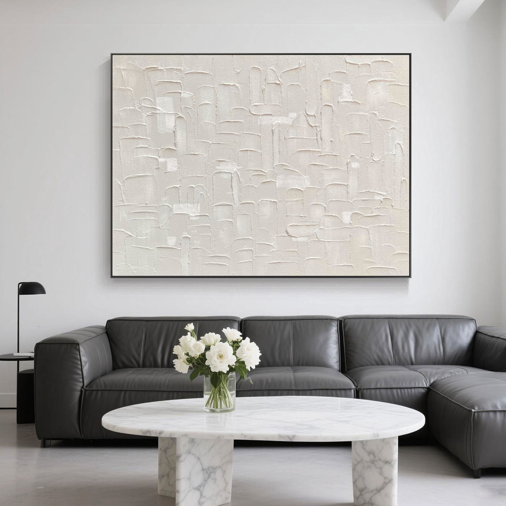 Beige art behind a gray sectional with marble furniture and floral accents.