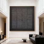 Hand-painted black geometric textured canvas with weathered grid, gold frame in modern living room at Lumi Gallery