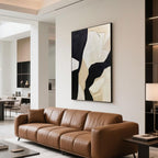Modern abstract geometric canvas art displayed above a tan leather sofa in a sleek apartment living room with warm lighting.