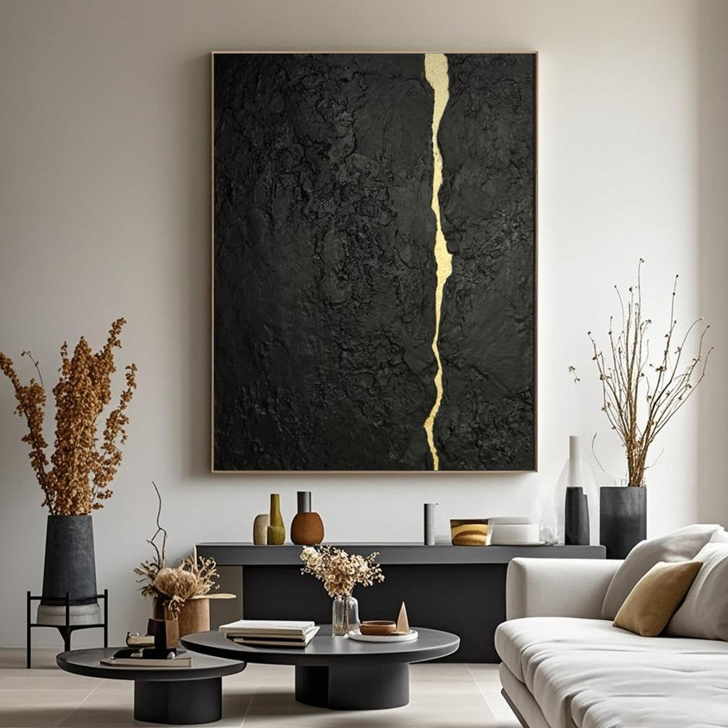 Abstract minimalist black gold canvas painting with kintsugi vein, mounted on a wall in a contemporary living room with neutral furnishings.