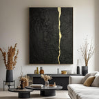 Abstract minimalist black gold canvas painting with kintsugi vein, mounted on a wall in a contemporary living room with neutral furnishings.