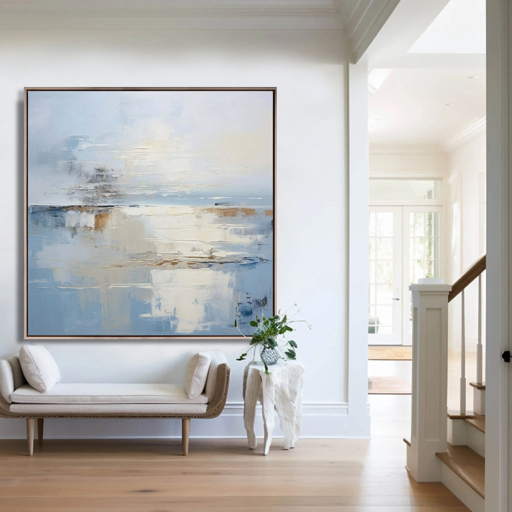 Abstract minimalist blue coastal wall art 'Harbour' with textured brushstrokes in soft blues, whites, and beiges, displayed in a modern living room setting.